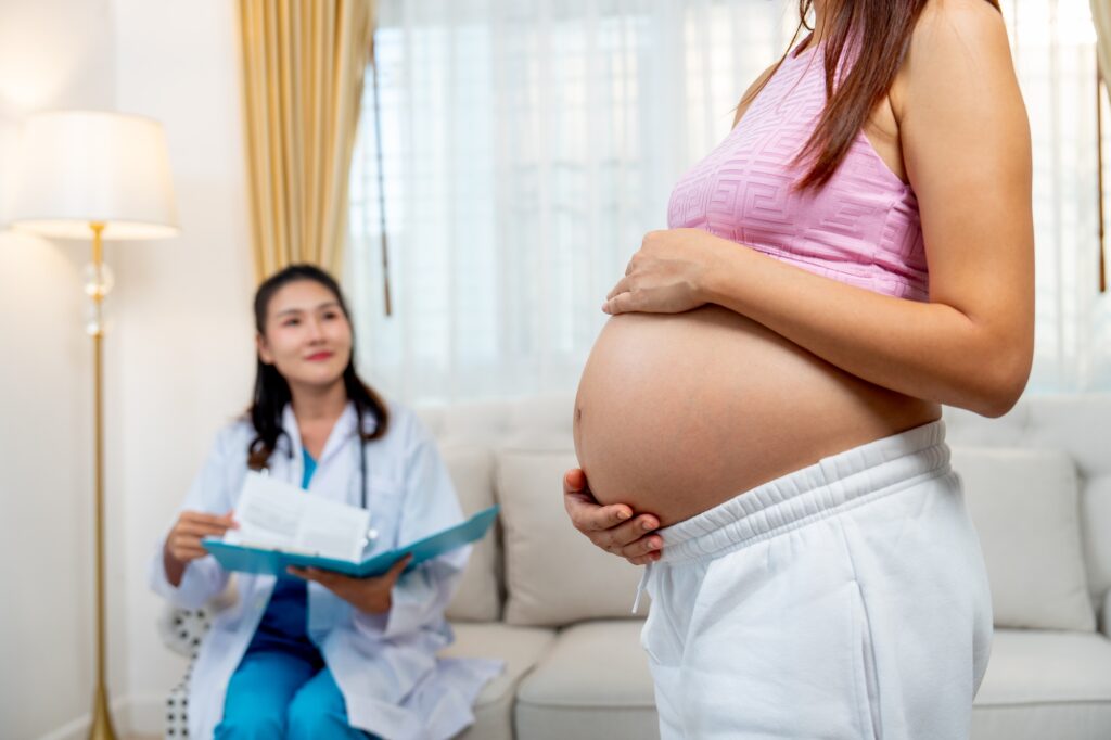 Pregnant woman stand in front of nurse or doctor check the data or healthcare result document